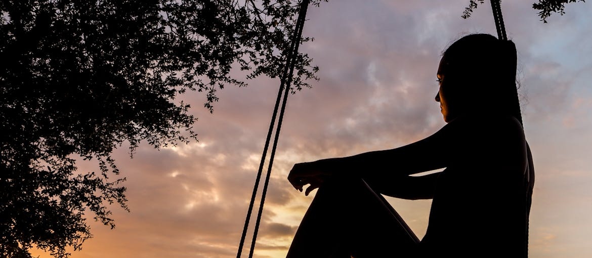 Woman sitting on a swing and looking at the sky.