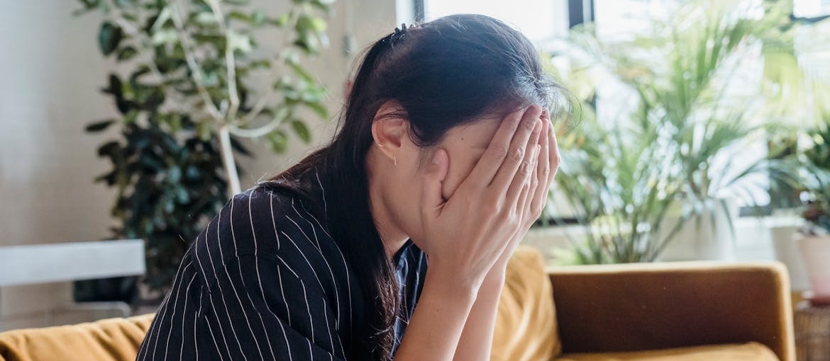 Woman covering her face and wondering how to stop intrusive thoughts.