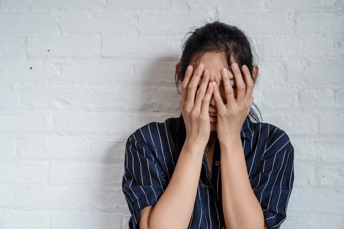 Woman covering her face and wondering how to stop intrusive thoughts.