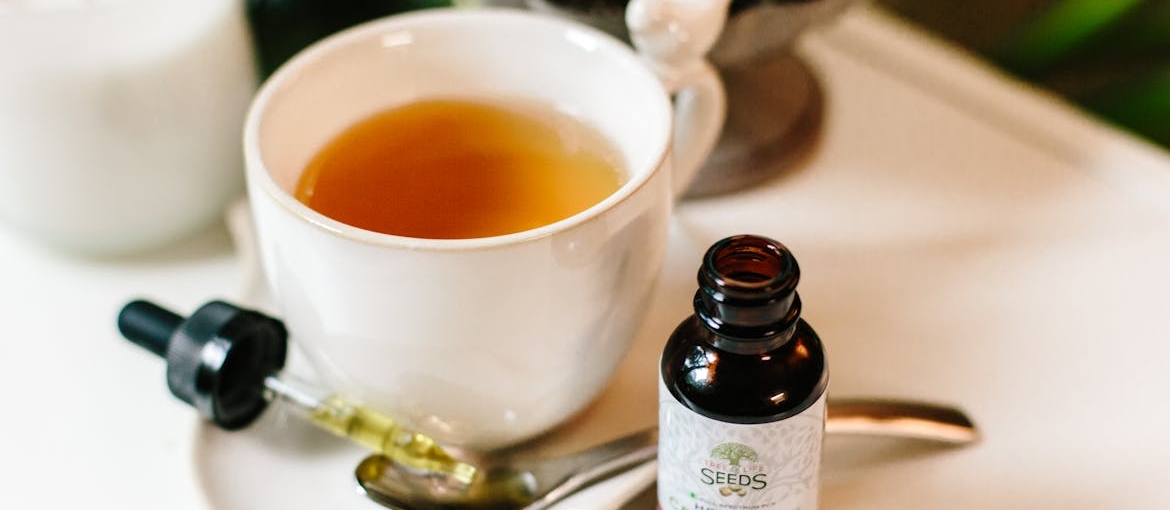 CBD oil next to a cup of tea.