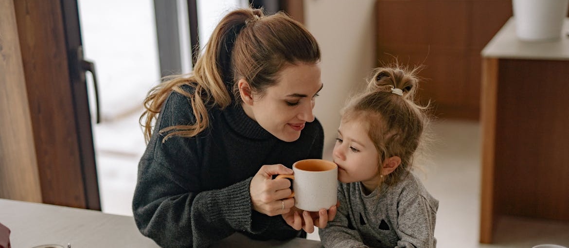 Woman sharing her drink with a young girl.