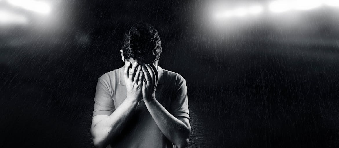 Black and white picture of a man covering his face.