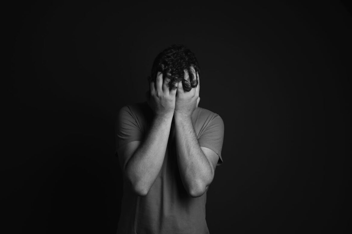 Stressed out man covering his face with his hands.