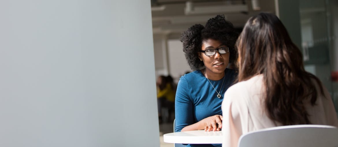 Two women talking about alcohol abuse and poverty in a counseling session.