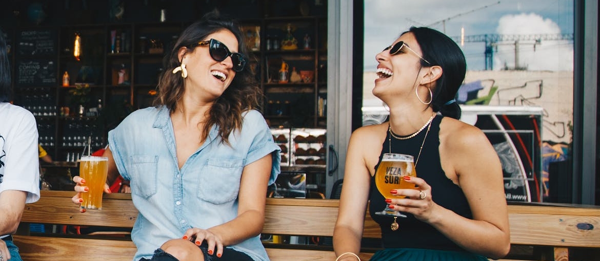 Two women sitting in a restaurant and drinking beer.