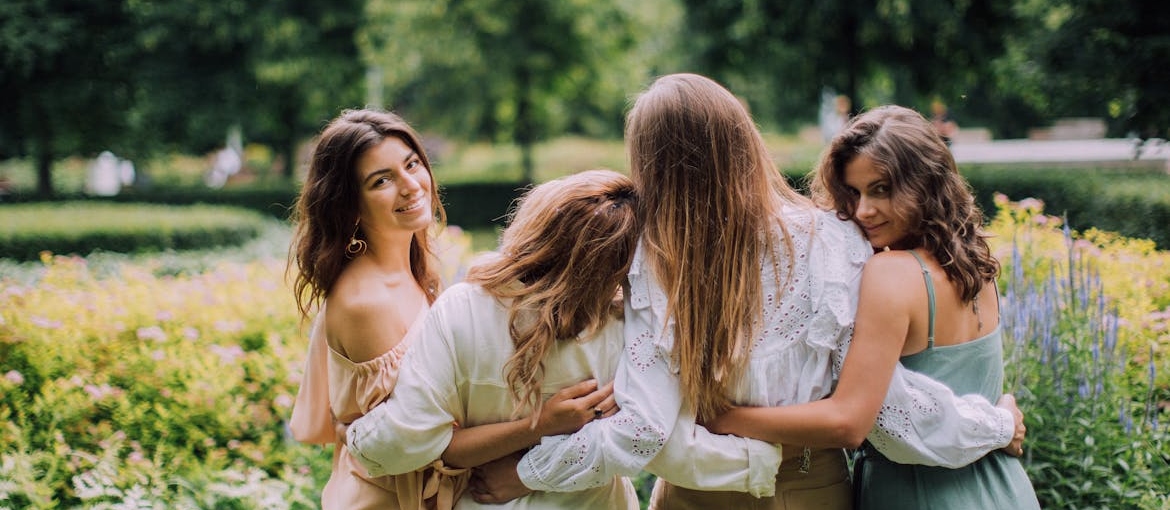 Four women hugging and talking about self care tips for women.