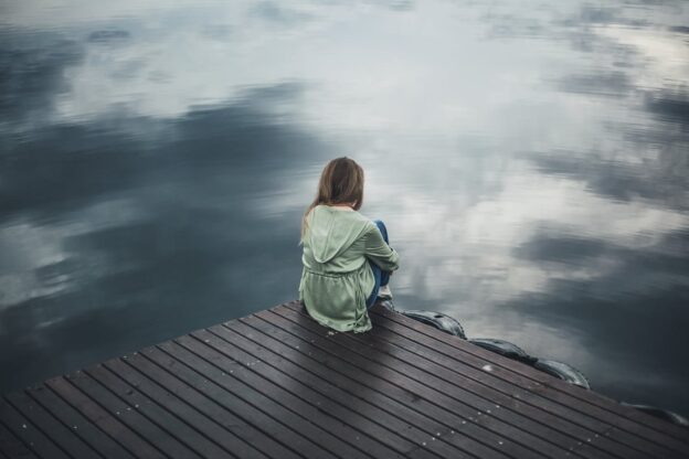 Woman sitting on the dock while struggling with both seasonal affective disorder and addiction.