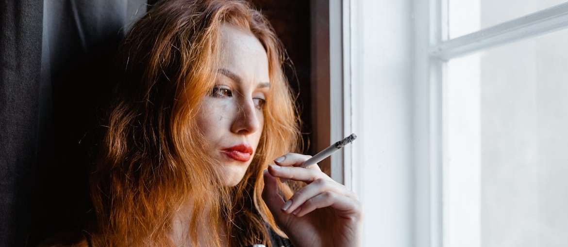 Woman smoking and looking out of the window.