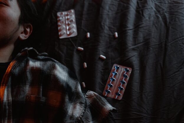 Man lying next to empty blisters of pills.