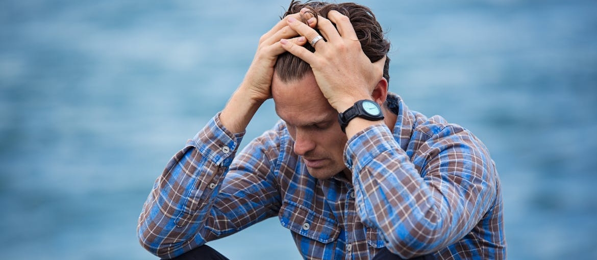 Stressed out man gripping his head.