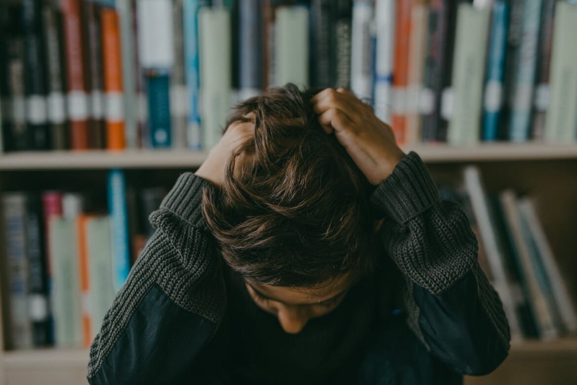 Little boy holding his head in the middle of the library.