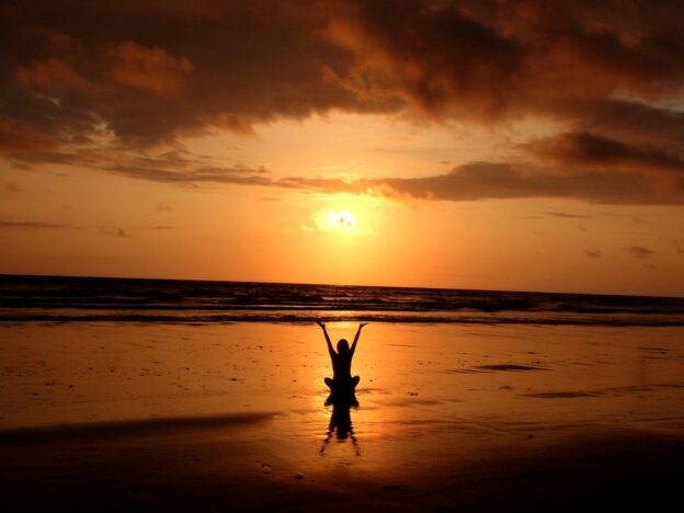 Woman sitting on the beach and experiencing mental wellness.