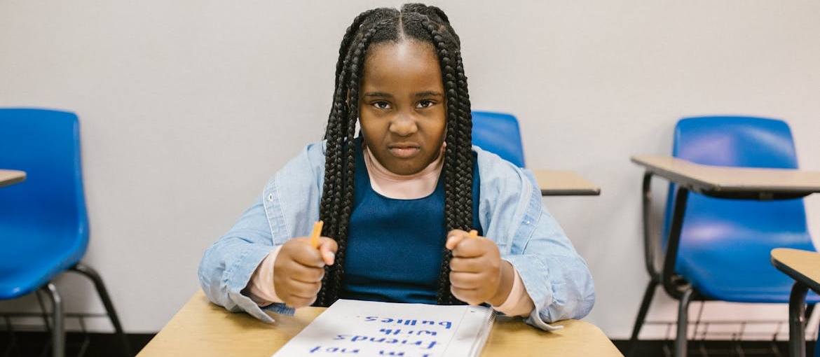 Angry young girl sitting in a classroom.