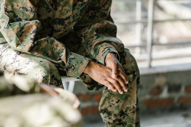 Man in military clothing rubbing his hands.