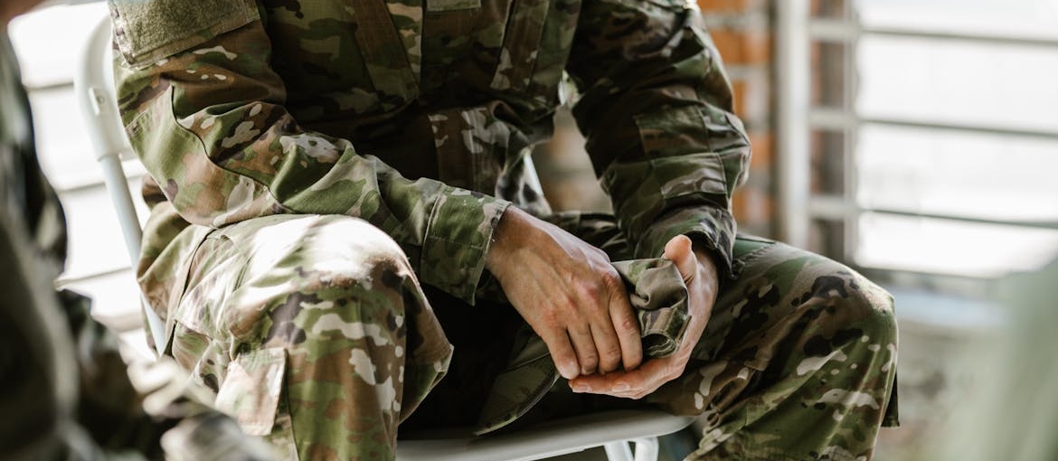 Man in military clothing holding a cap.