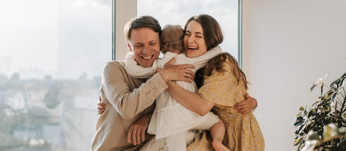 Couple hugging a girl toddler.