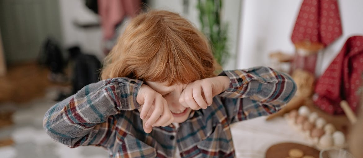 Young boy crying while experiencing the bad impact of parental addiction on child development.