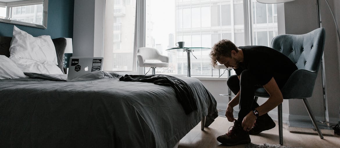 Man sitting on a chair and tying his shoes.