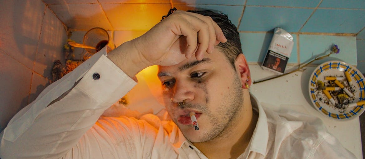 Man lying in a bathtub and smoking a cigarette.