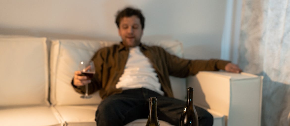 Man sitting on the couch and drinking a glass of wine.