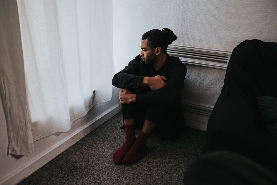 Man sitting by a window reflecting on how drugs can affect thoughts and behavior.