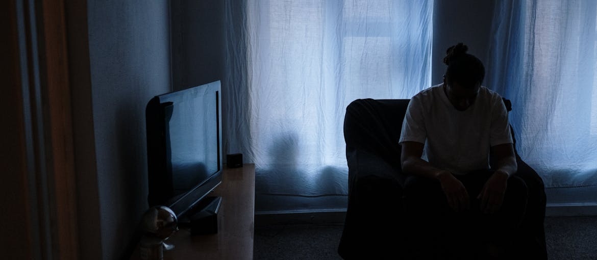 Man sitting alone in a dimly lit room.