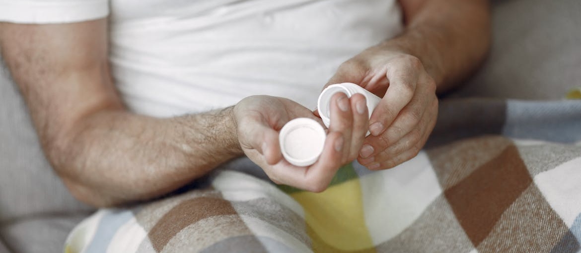 Person lying in bed and taking a pill.
