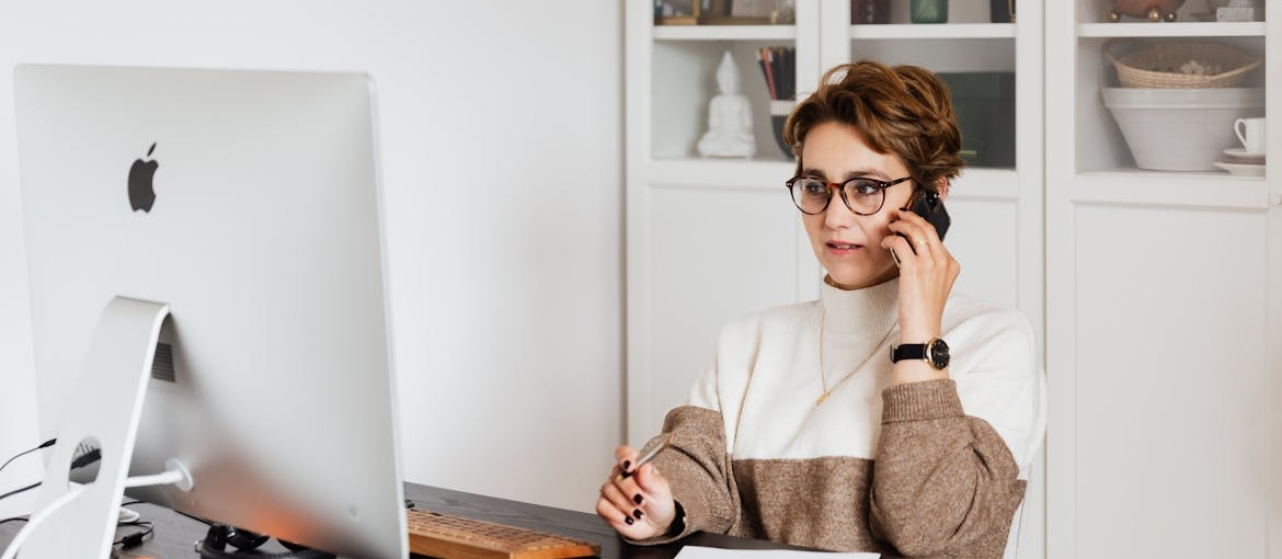 Woman talking on the phone while looking up rehab centers on her computer.