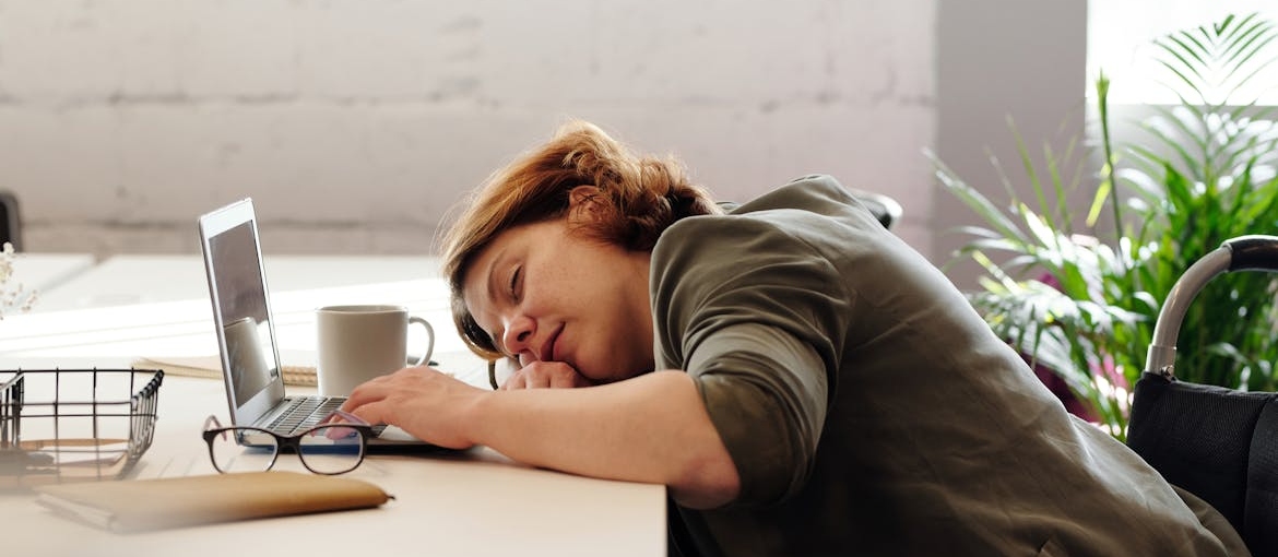 Woman sleeping on the table at work while experiencing Lexapro withdrawal symptoms.