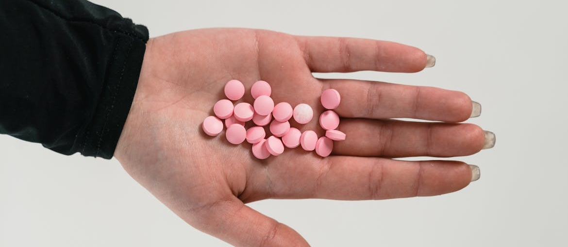 Woman holding pills in her hand.