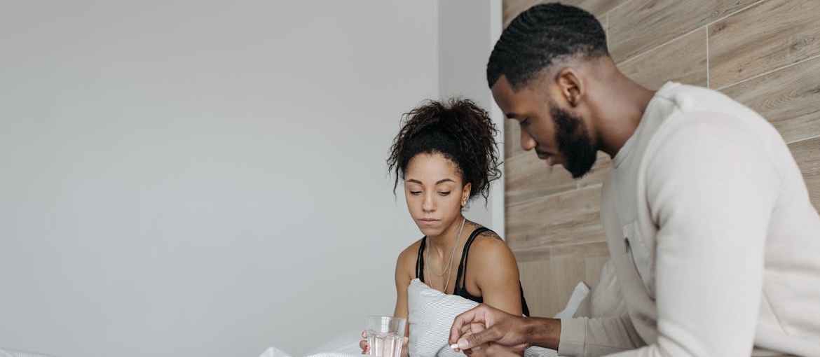 Man giving a pill to a woman who is experiencing Xanax withdrawal symptoms.