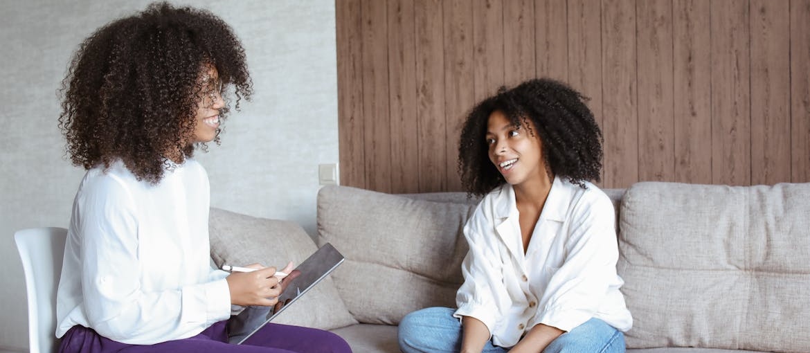 Woman sitting on the couch and smiling while talking to her therapist.