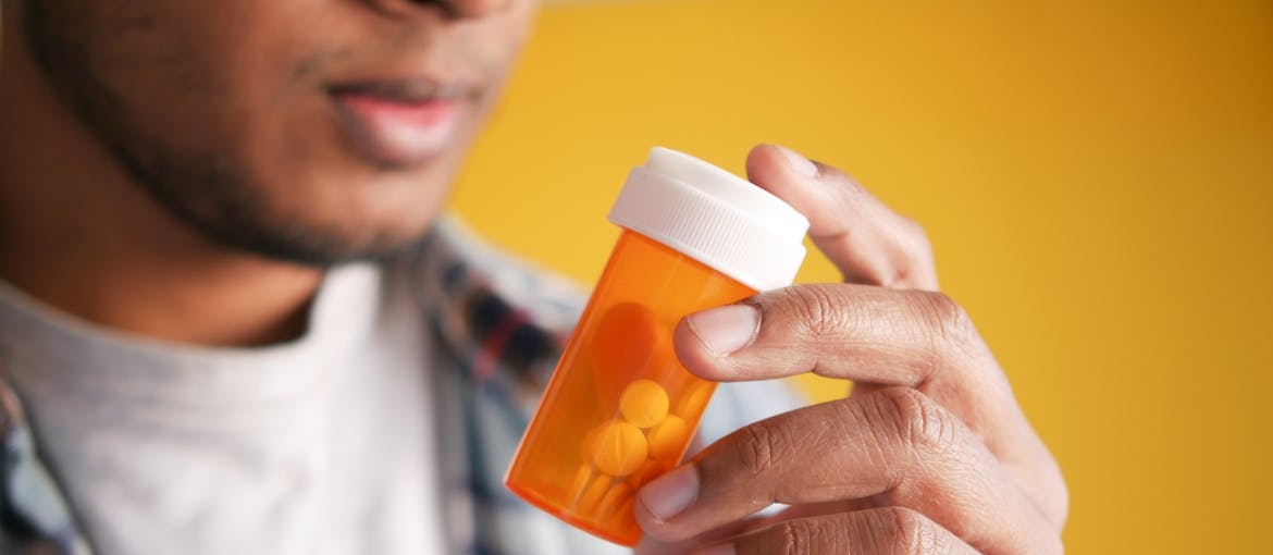 Man holding an orange bottle of pills.