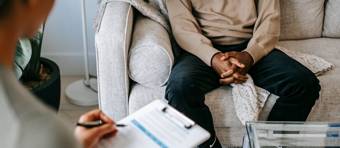 Therapist writing in a clipboard and talking with a patient.