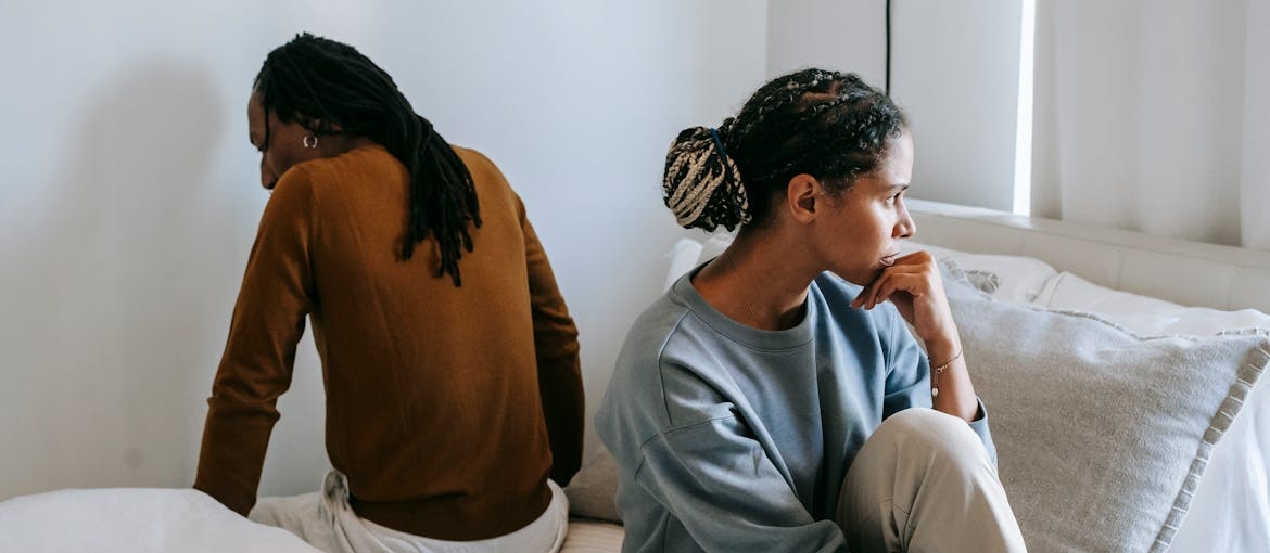 Couple sitting on the bed after arguing about toxic behavior and addiction.