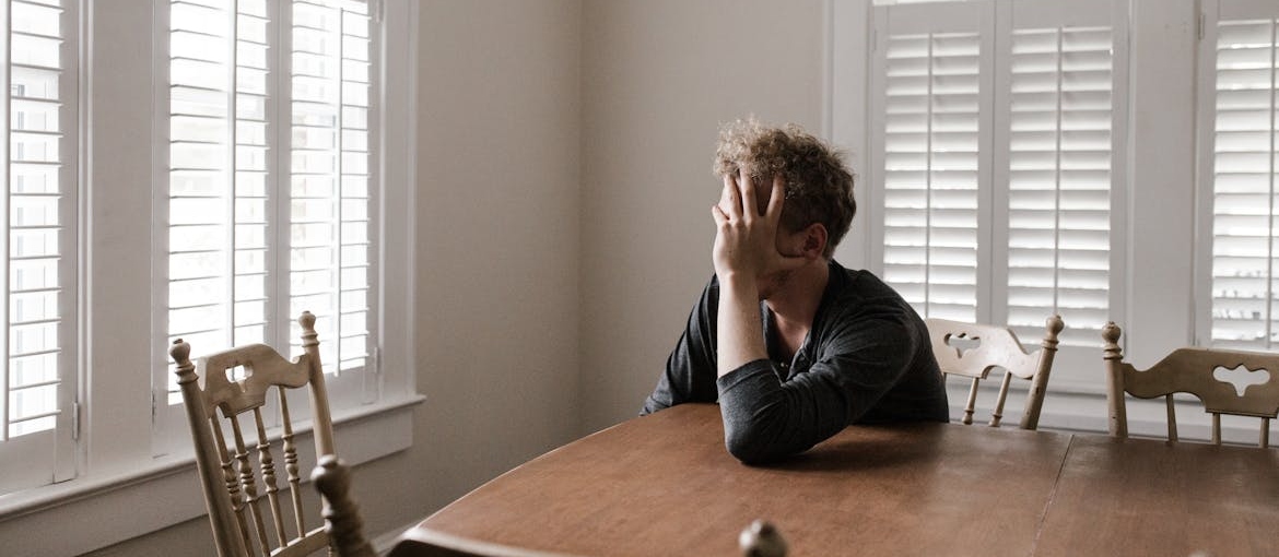 Man sitting at the table and holding his head in his hands.