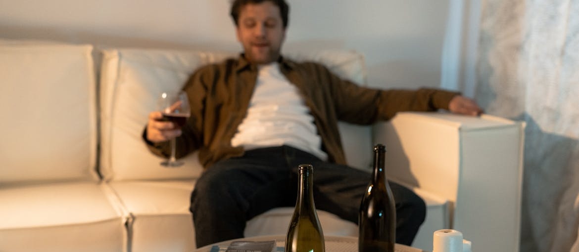 Man sitting on the couch and drinking wine.
