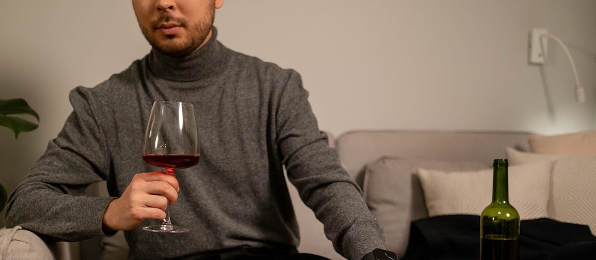 Man sitting on the couch and drinking wine.