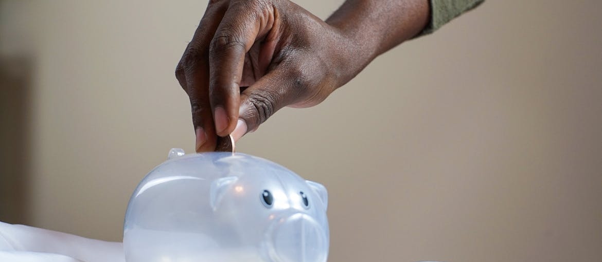 Person putting a coin in a piggy bank.