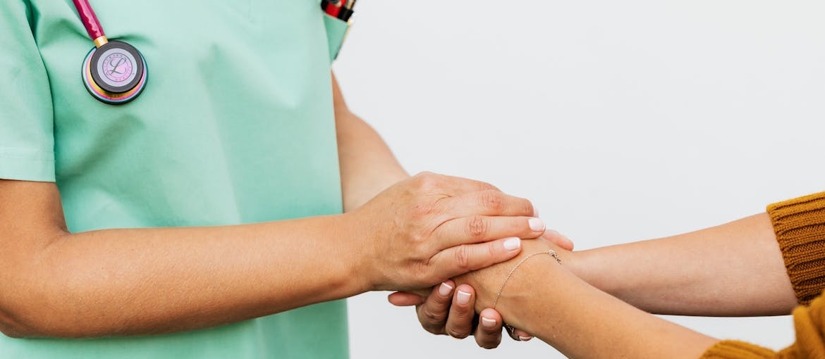 Nurse holding a patient's hands.