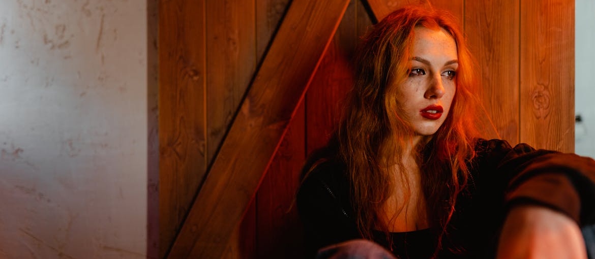 Woman crying and drinking beer while sitting on the floor.