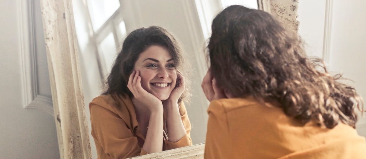 Woman looking at herself in the mirror and smiling.