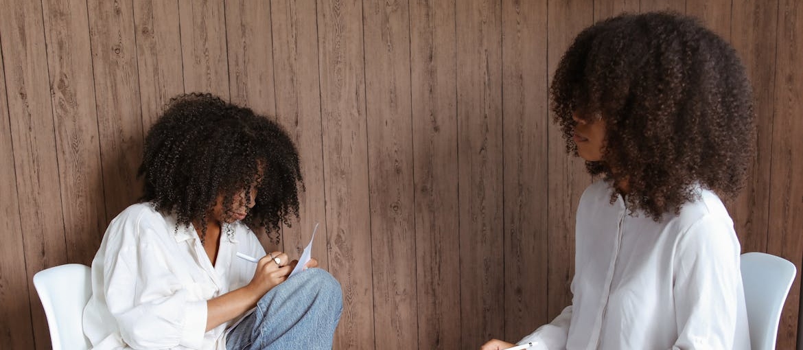 Woman writing on a piece of paper in therapy.