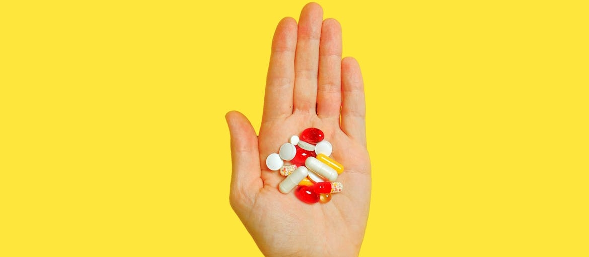 Person holding delirium tremens medication and vitamins in their hand.