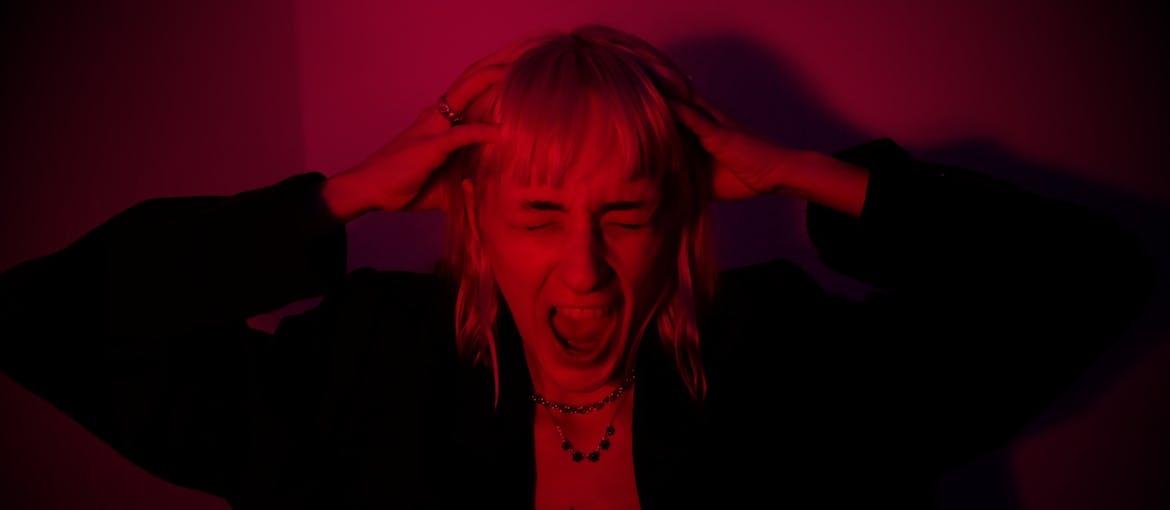 Woman screaming and holding her head while experiencing paranoia.