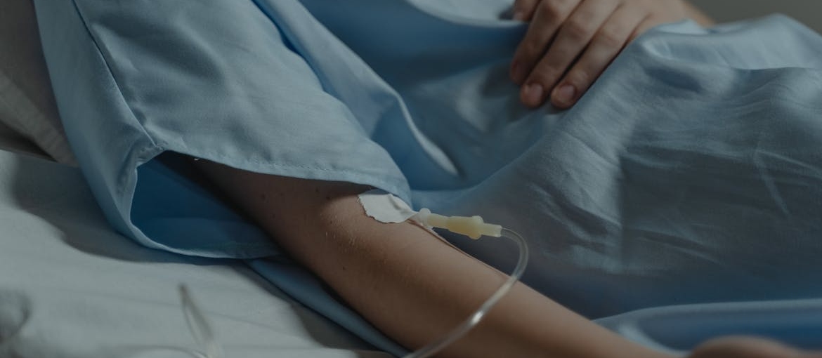 Woman sitting in a hospital bed with an IV in her hand.