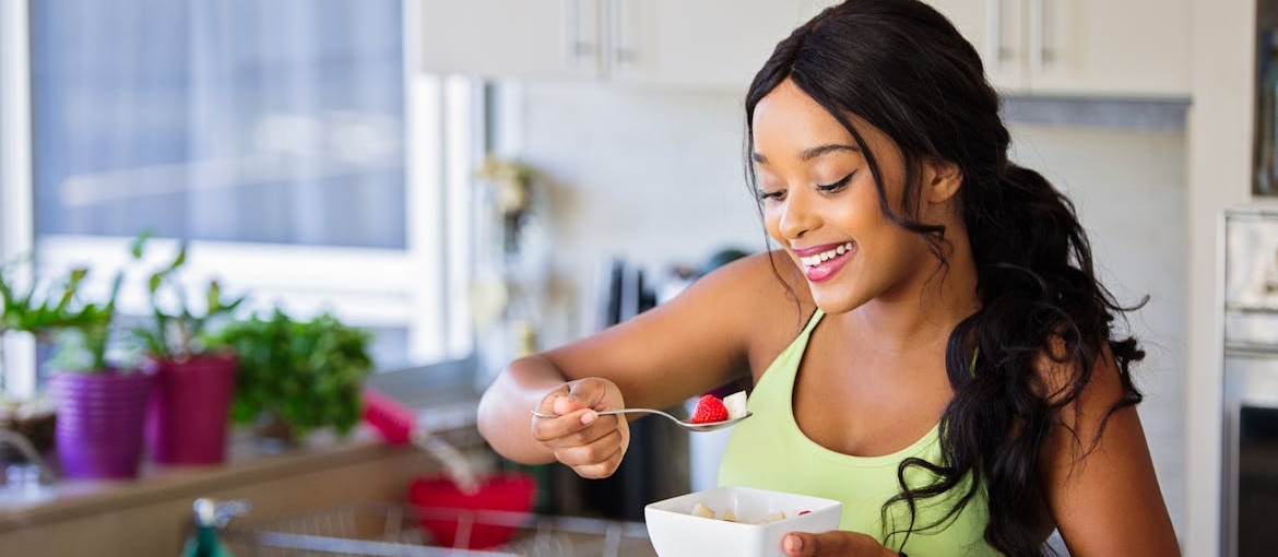 Woman eating a fruit salad in her kitchen.