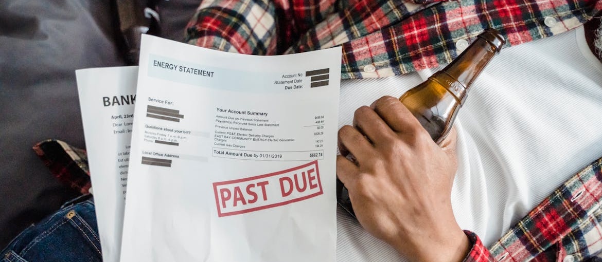 Empty beer bottles and unpaid bills demonstating the link between socioeconomic status and addiction.
