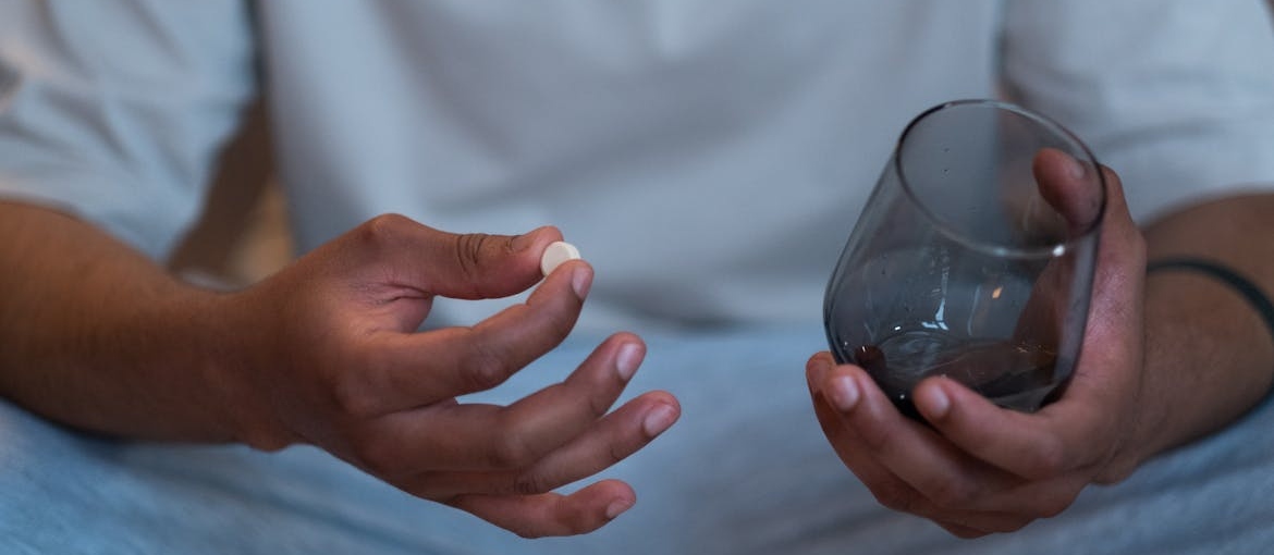 Man holding a pill and a glass of water.