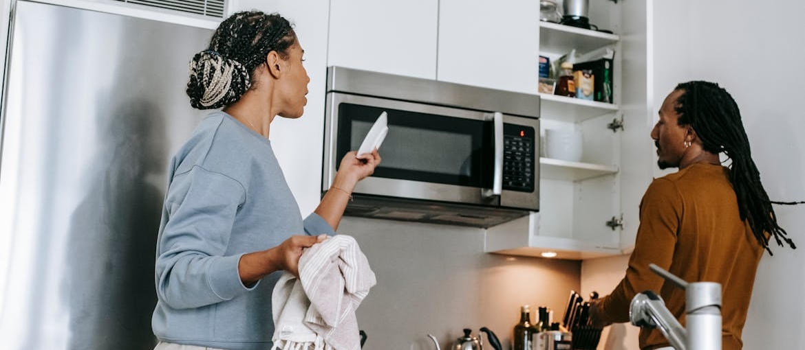 Siblings washing and drying dishes and having an argument.
